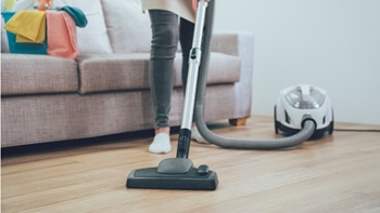 personne passant l'aspirateur sur du parquet